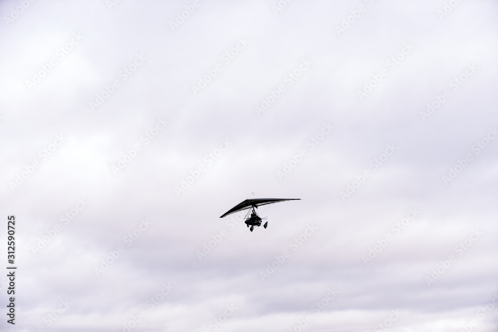 Person flying away into the horizon on a small aircraft single seat microlight as a hobby or sport in the air Person flying away into the horizon on a small aircraft single seat microlight as a hobby or sport in the air