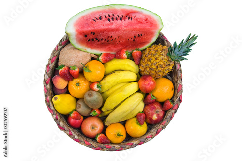 A beautiful basket of tropical fruits seen from above with pineapple, watermelon, bananas, clementines, papaya, strawberry, orange, peaches, kiwi and coconut