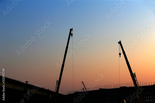 A silhouette of a crane working at a construction site