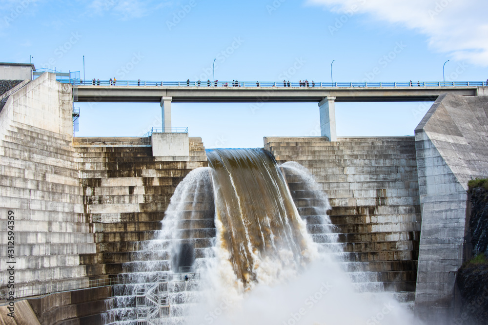 Water flowing from weir as people watch overhead