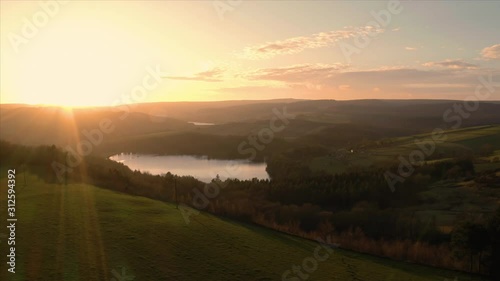 Aerial fly over calm lake and Agden Reservoir during sunset. Bradfield village, Sheffield, Peak District National Park, Yorkshire and Derbyshire, UK. December 2019.