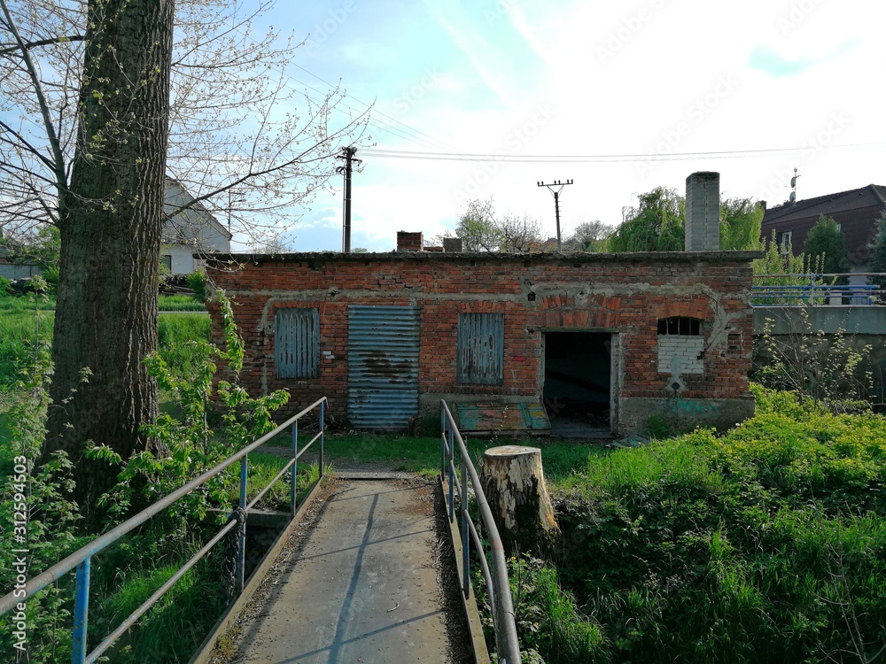 Building old and abandoned, standing by the bridge, its windows are closed by sheets steel Building old and abandoned, standing by the bridge, its windows are closed by sheets steel