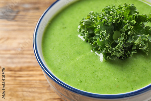 Tasty kale soup on wooden table, closeup