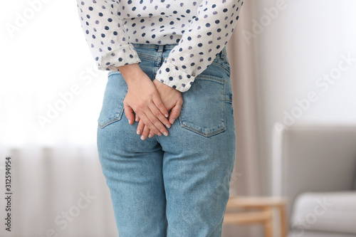 Young woman suffering from hemorrhoid at home, closeup photo