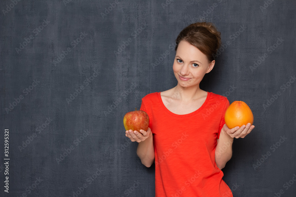 Portrait of happy young woman smiling and holding grapefruit and apple Portrait of happy young woman smiling and holding grapefruit and apple