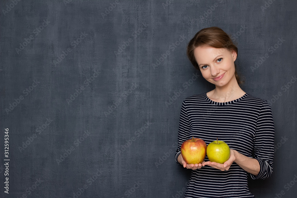 Portrait of happy young woman smiling and holding two apples in hands Portrait of happy young woman smiling and holding two apples in hands