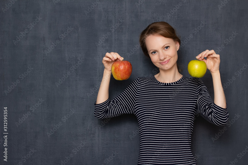 Portrait of happy young woman smiling and holding two apples in hands Portrait of happy young woman smiling and holding two apples in hands