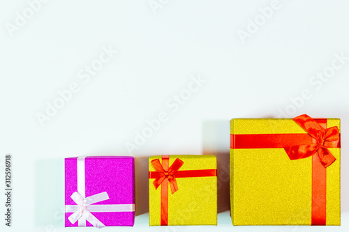 2019.12.29, Moscow, Russia. Three bright gift boxes with red ribbon on a white background. Concept of Happy birthday or another festival.
