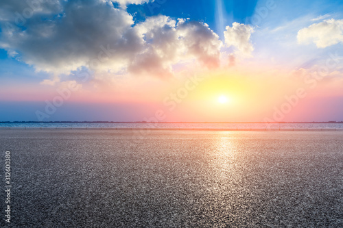 Fototapeta Naklejka Na Ścianę i Meble -  Empty asphalt road and lake with dreamy clouds at sunset.