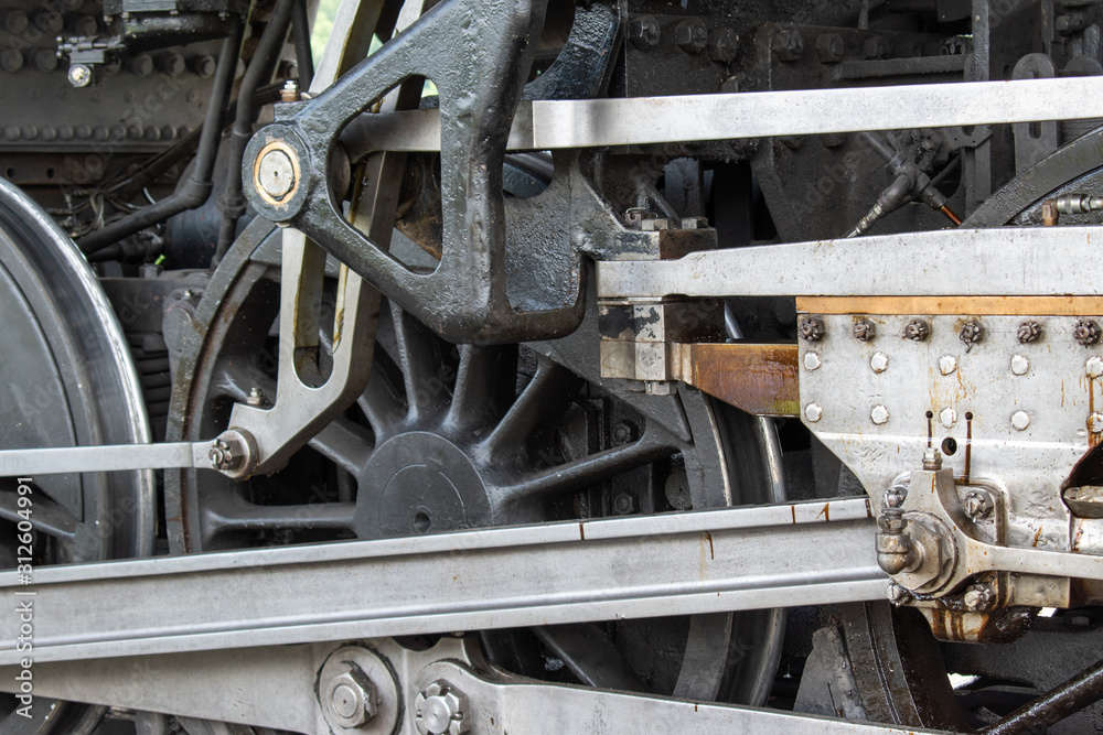 Fototapeta premium The silver and black metal shine in a close up of a steam engine wheel