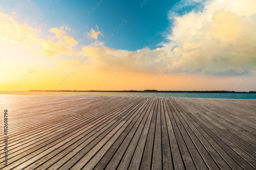 Obraz premium Lakeside wood floor platform and sky clouds at sunset.