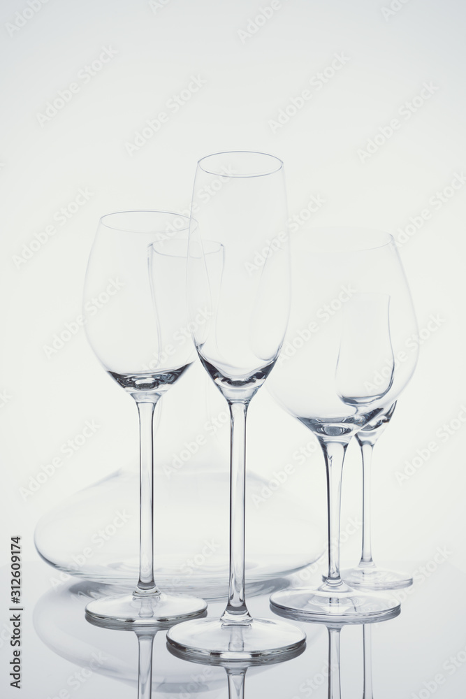 Glassware selection with wine, champagne, liquour glasses and decanter on the light background.. Fine cristal glassware concept. Vertical, cold tone in light cold toning Glassware selection with wine, champagne, liquour glasses and decanter on the light background.. Fine cristal glassware concept. Vertical, cold tone in light cold toning