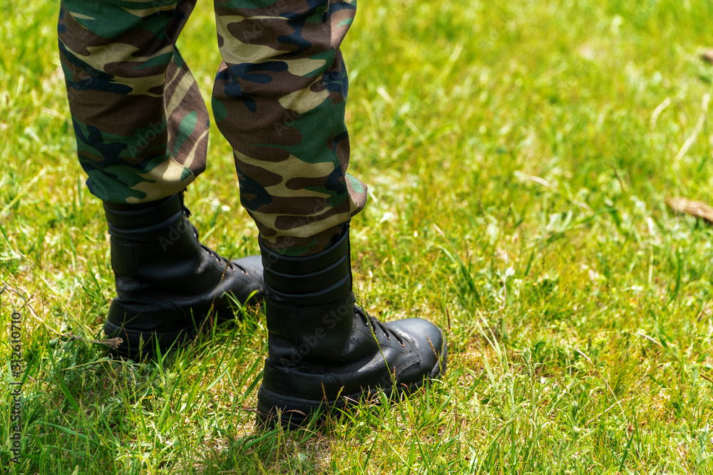 Black leather soldier boots on green grass. Black leather soldier boots on green grass.