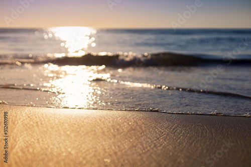 Sunset beach wave from sea come to beach with sun light reflect on water sea soft focus and focus selective to soft wave and sand. with copy space for text or design.