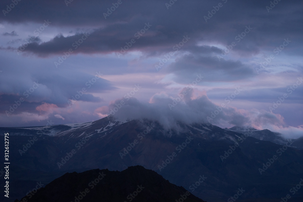 Mountain peak with snow and clouds during dramatic and colorful sunset Mountain peak with snow and clouds during dramatic and colorful sunset