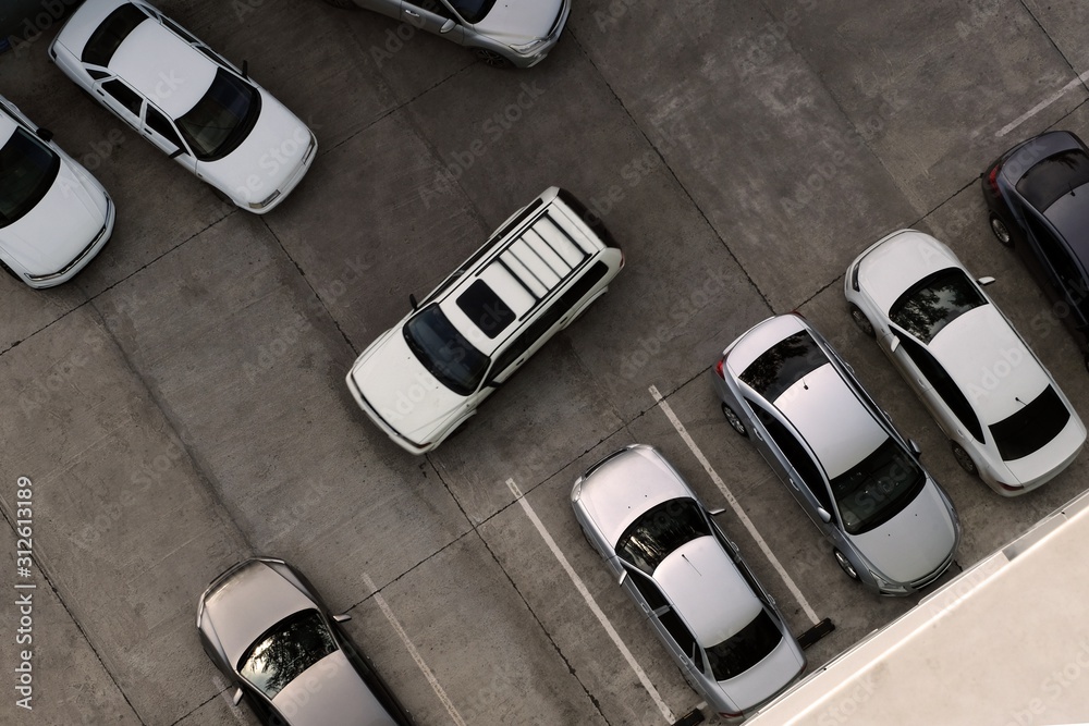 A car drives into an empty parking space among various other cars. View from above. Concept. Copy space.