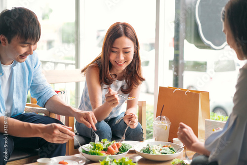 cheerful multiracial friend smiling and eating healthy food in a restaurant, group of happy friend concept