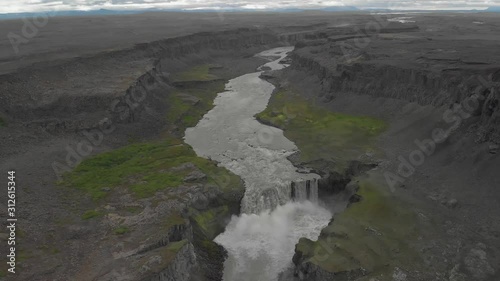 Backward drone shot of a massive waterfall overlooking the river down the horizon. This was taken at a regular speed with natural motion blur. photo