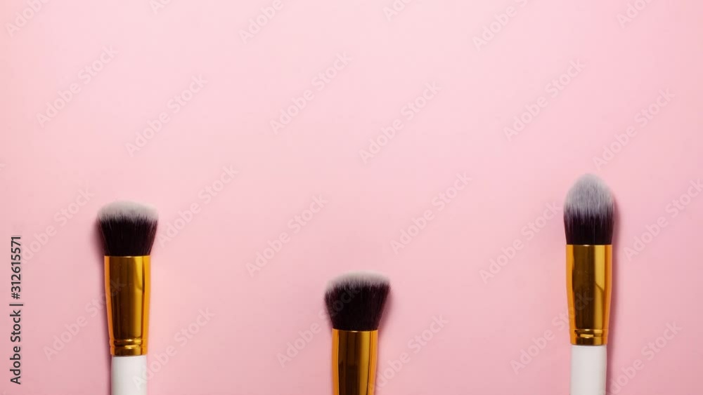 Stop motion animation top view of cosmetics brushes set for makeup at the bottom on pink background. Cosmetics and beauty concept. Make up concept with space for text