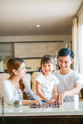 parent teaching their daughter saving money in piggy bank