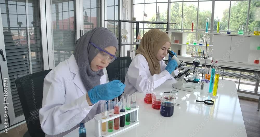 Two young Muslim female researchers working happily in the laboratory ...