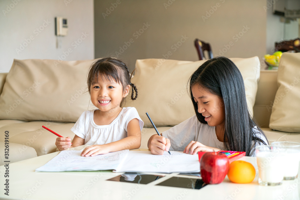 Asian beautiful girl doing their homework together in living room with smiling and happiness feeling , Asian happy family concept Asian beautiful girl doing their homework together in living room with smiling and happiness feeling , Asian happy family concept