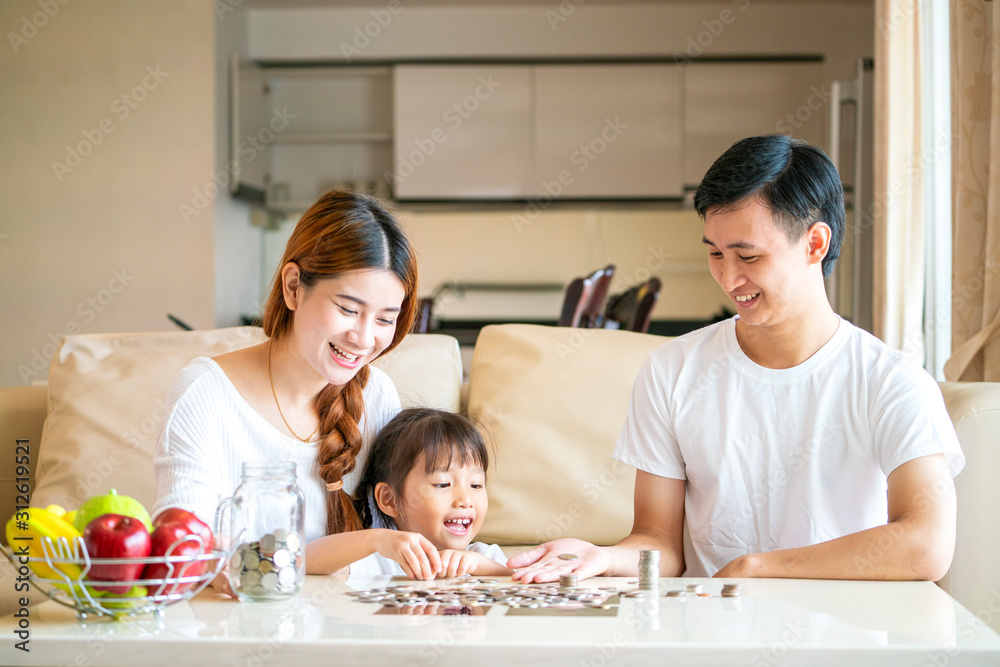 Asian family teach Asian cute girl saving money putting coins into piggy glass bank, vintage tone. education, save money, Asian family, investment, future investment or family relationship concept Asian family teach Asian cute girl saving money putting coins into piggy glass bank, vintage tone. education, save money, Asian family, investment, future investment or family relationship concept
