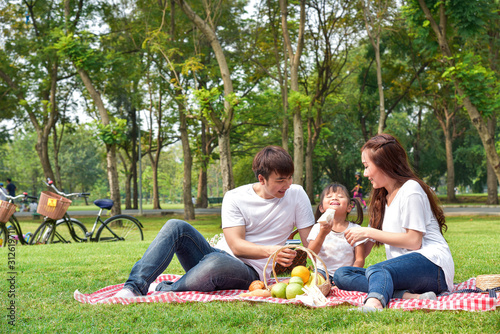 Portrait of happy Asian family, parents and daughter enjoying picnic meal in garden. Asian, Asian family, picnic, love, relationship, outdoors meal, park, family activities or happy garden concept