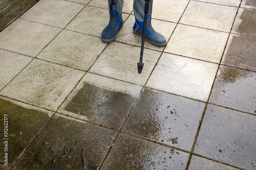 Outdoor floor cleaning with high pressure water jet. Man in rubber boots