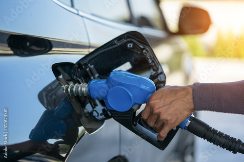 Pumping gas at gas pump. Closeup of man pumping gasoline fuel in car at gas station.
