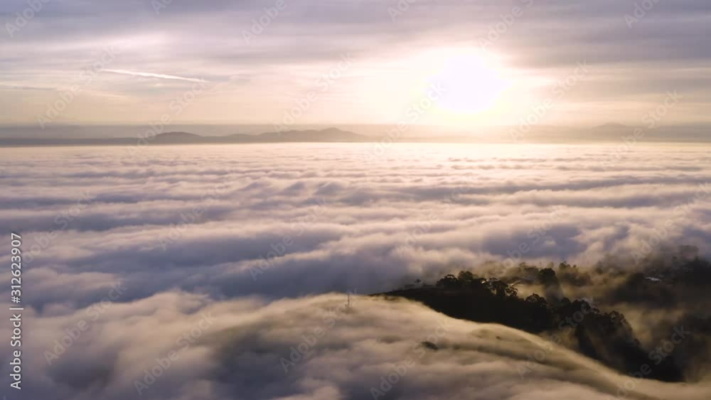 4K aerial sunset. Sunset above the clouds! The camera pushes forward and pans down over a sea of fog to focus on a cross sticking out of the fog. 4K aerial sunset. Sunset above the clouds! The camera pushes forward and pans down over a sea of fog to focus on a cross sticking out of the fog.