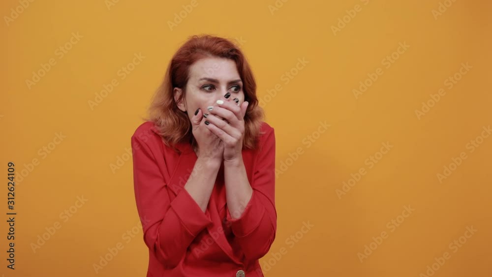 Scared caucasian young woman covering mouth with hand, looking at camera wearing fashion red jacket over isolated orange background. People lifestyle concept. Scared caucasian young woman covering mouth with hand, looking at camera wearing fashion red jacket over isolated orange background. People lifestyle concept.