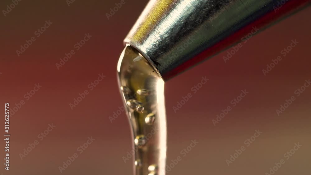 Macro extreme close up hot glue dripping out from metal nozzle Stock