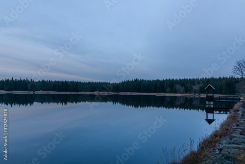 Ponds in Krusne hory mountains in winter cloudy evening
