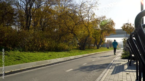 Wallpaper Mural Running male athlete runs into the street at dawn on the waterfront in a city park. Sports jogging, training, training in the open air in the summer. 4k footage. Torontodigital.ca
