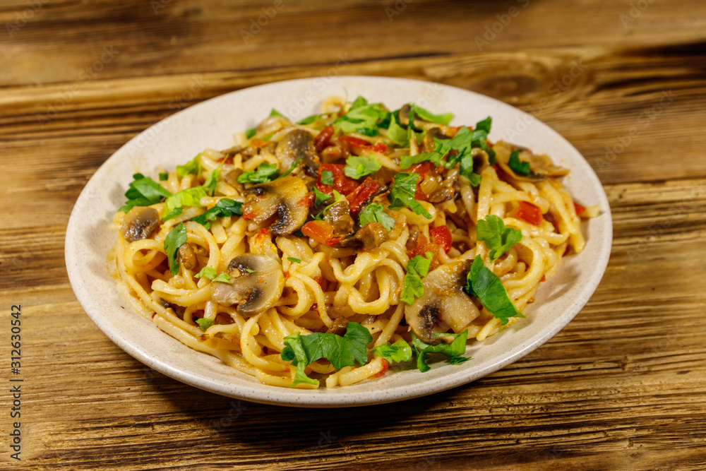 Pasta with mushrooms and tomato sauce on wooden table Pasta with mushrooms and tomato sauce on wooden table