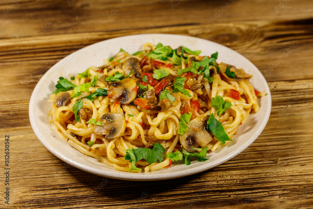 Pasta with mushrooms and tomato sauce on wooden table