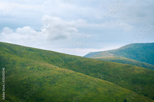 Beautiful mountain landscape with clouds. The road on the green top of Mount Ghimba in the Carpathians.
