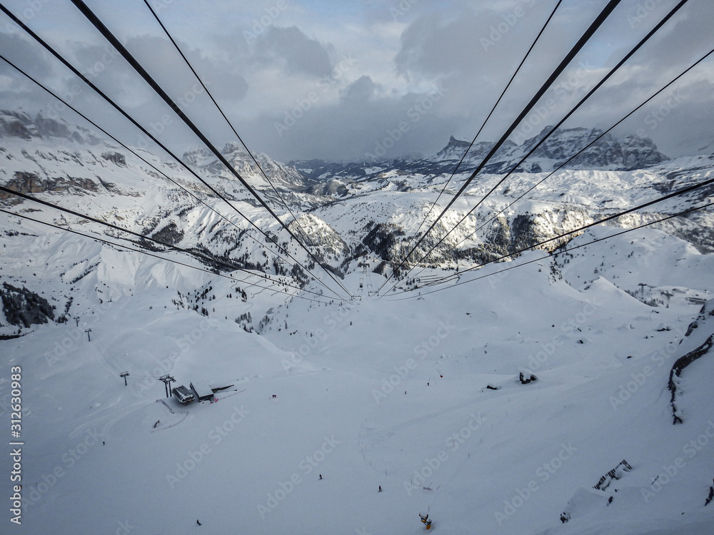 Gondola cables in the Dolomites with mountains, clouds, and snow Gondola cables in the Dolomites with mountains, clouds, and snow