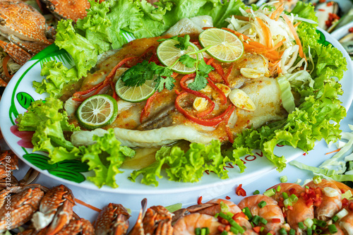 Seafood set. Steamed fish with lemon in a saucer with green vegetables.