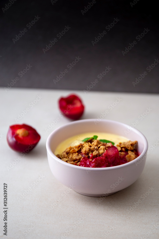 Fresh bright red plum crumble in the pink bowl Fresh bright red plum crumble in the pink bowl