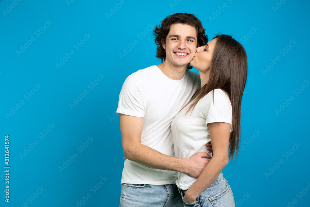 Naklejka premium Pretty girl kissing boyfriend isolated on blue background