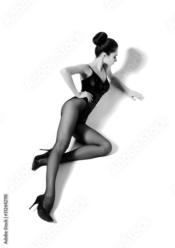 Beautiful fashion model in black swimsuit and hosiery. Young and beautiful woman posing in studio.