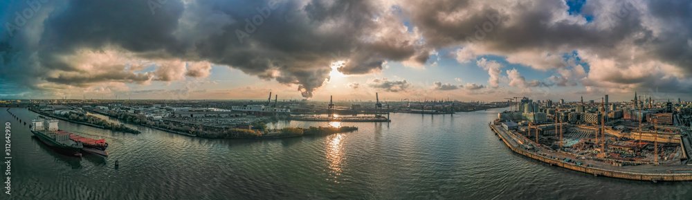 Panoramic drone aerial view of port of Hamburg from Hafencity before sunset with dramatic stormy clouds