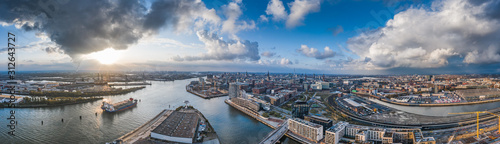 Aerial drone panoramic view of port of Hamburg from above before sunset with dramatic stormy clouds over the sea port