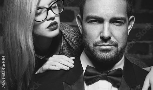 Sensual young woman seducing sexy macho man in tuxedo