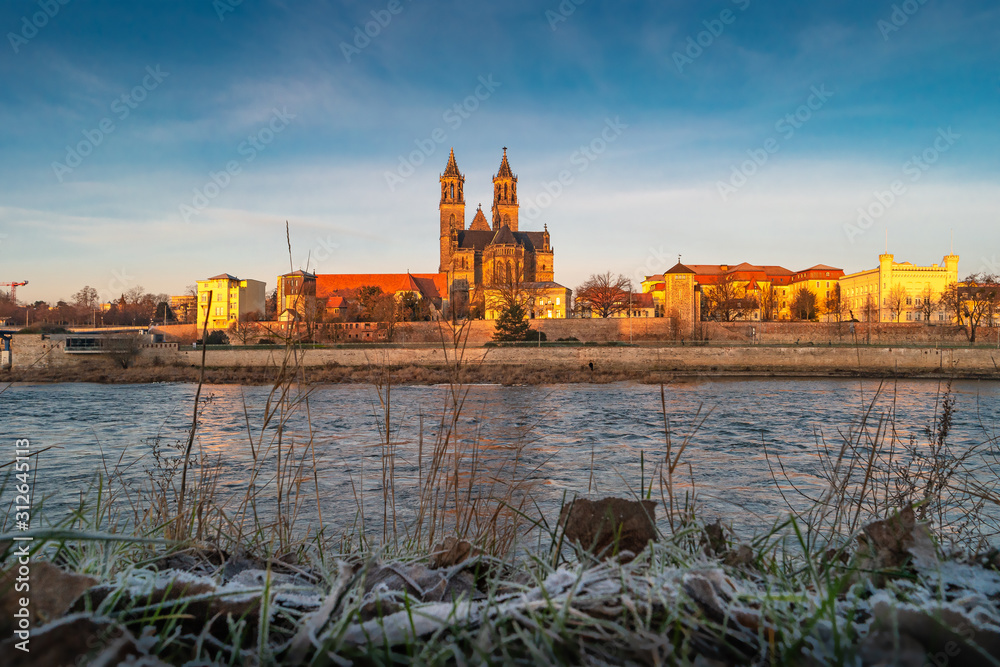 Magnificent Cathedral, Elbe river in golden sunrise colors at downtown of Magdeburg, city center, Magdeburg, Germany, sunny frosty morning, blue sky Magnificent Cathedral, Elbe river in golden sunrise colors at downtown of Magdeburg, city center, Magdeburg, Germany, sunny frosty morning, blue sky