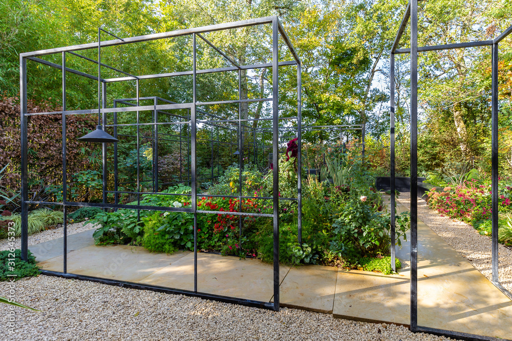 Urban garden design with a black steel frame enclosing the walkway through the garden