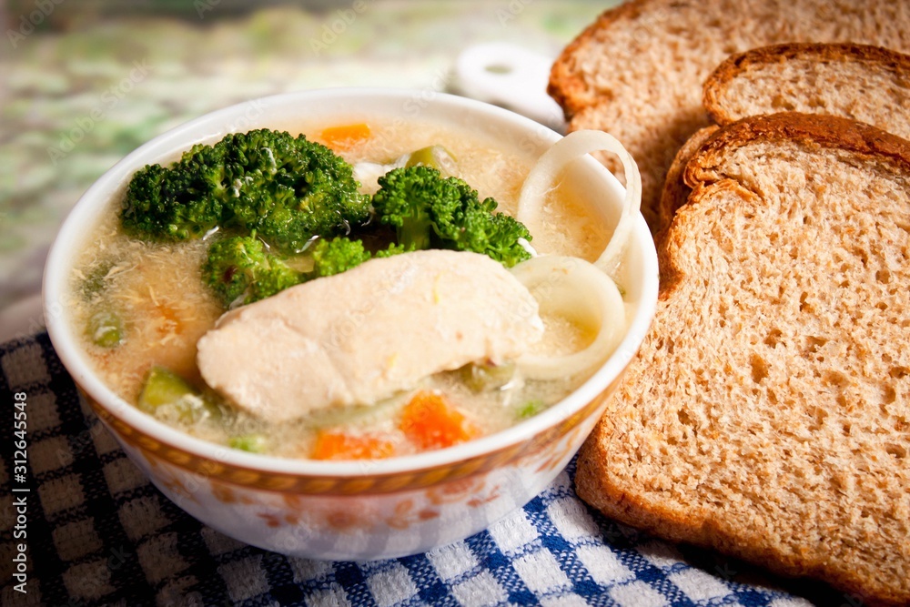 Cream soup with bread and stuffed broccoli as well as other fresh vegetables, served with a delicious small bowl of boiled chicken on a wooden table Cream soup with bread and stuffed broccoli as well as other fresh vegetables, served with a delicious small bowl of boiled chicken on a wooden table