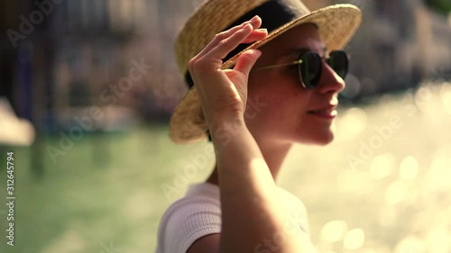 Slow motion effect of happy smiling female traveller in summer outfit enjoying sightseeing on touristic boat excursion around romantic city Venice looking around and feeling prosperous. Vacations